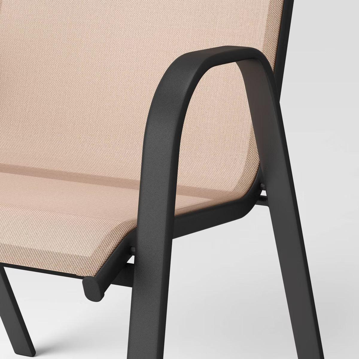 A chair with a beige colored fabric seat and backrest, featuring a black colored metal frame and armrests