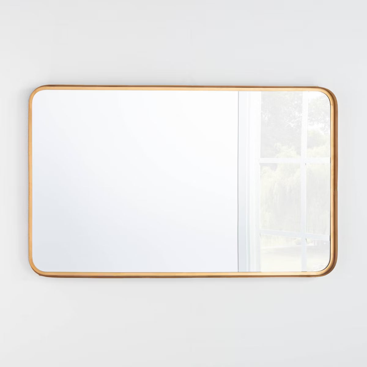 Rectangular mirror with a gold frame on a white wall brass