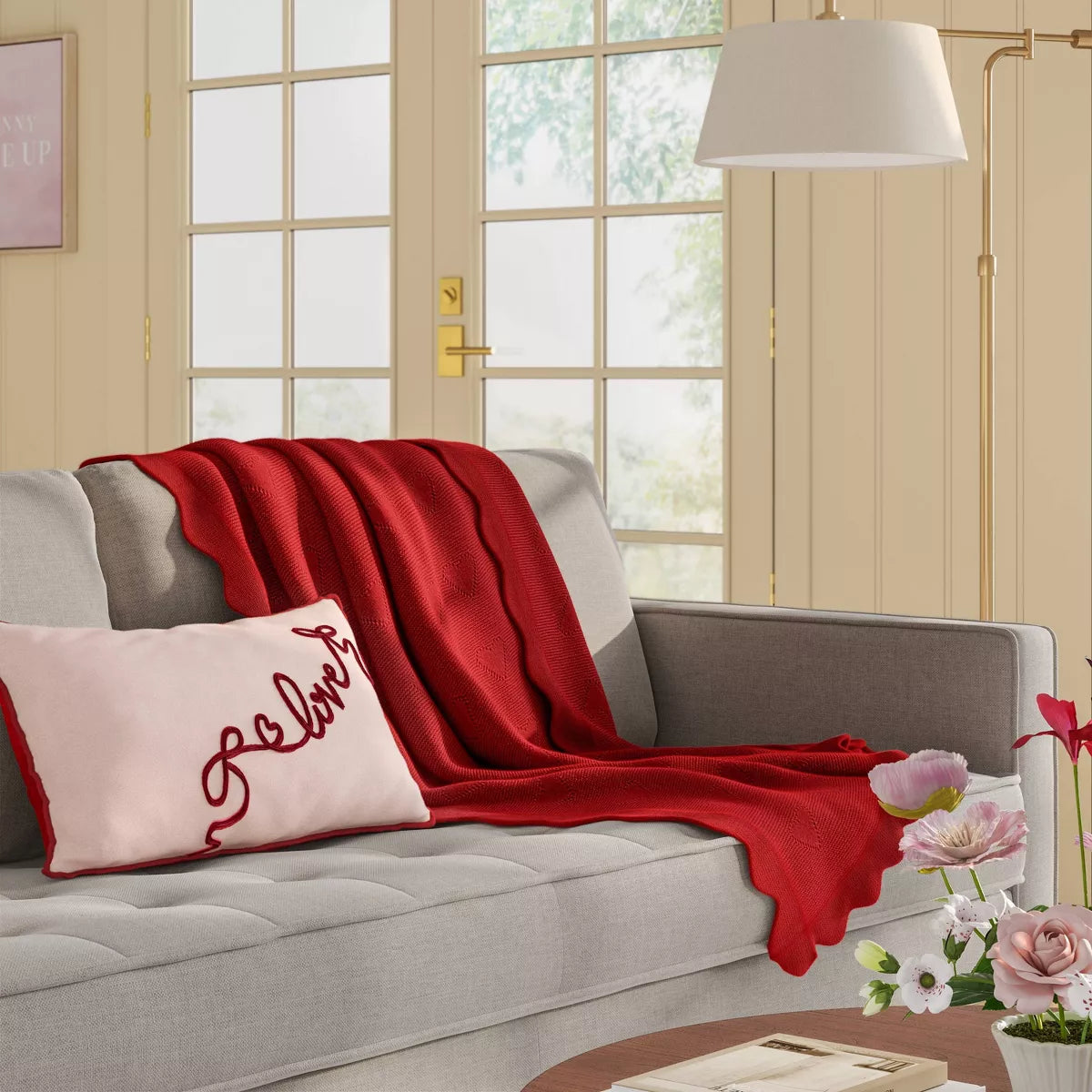 Rectangular light pink colored pillow with red colored piping and the word & quot love quot embroidered in red.