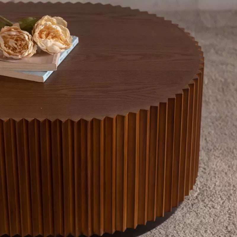 Wooden coffee table with a textured surface, featuring a book and flowers on top.