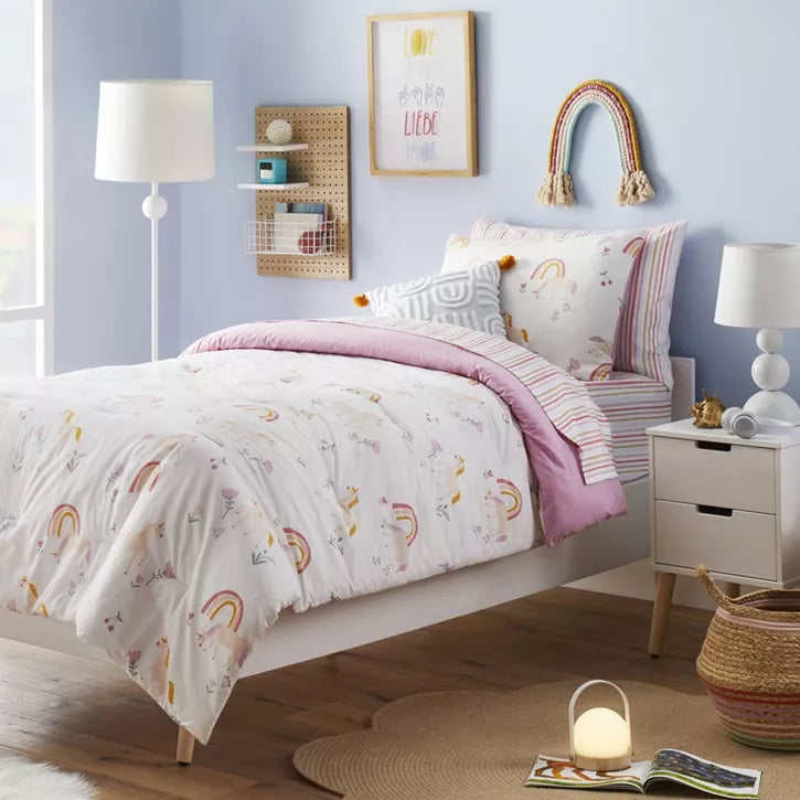 Bedroom with floral bedding and colorful pillows on a bed against a pink wall.