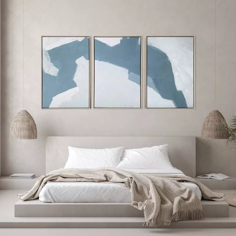 Three abstract wall art pieces above a bed in a bedroom setting.
