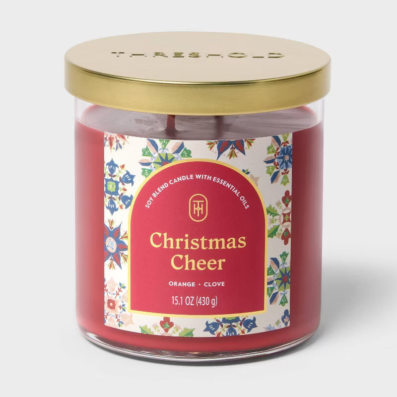 Candle labeled 'Christmas Cheer' on a table with a decorative background 15.1oz