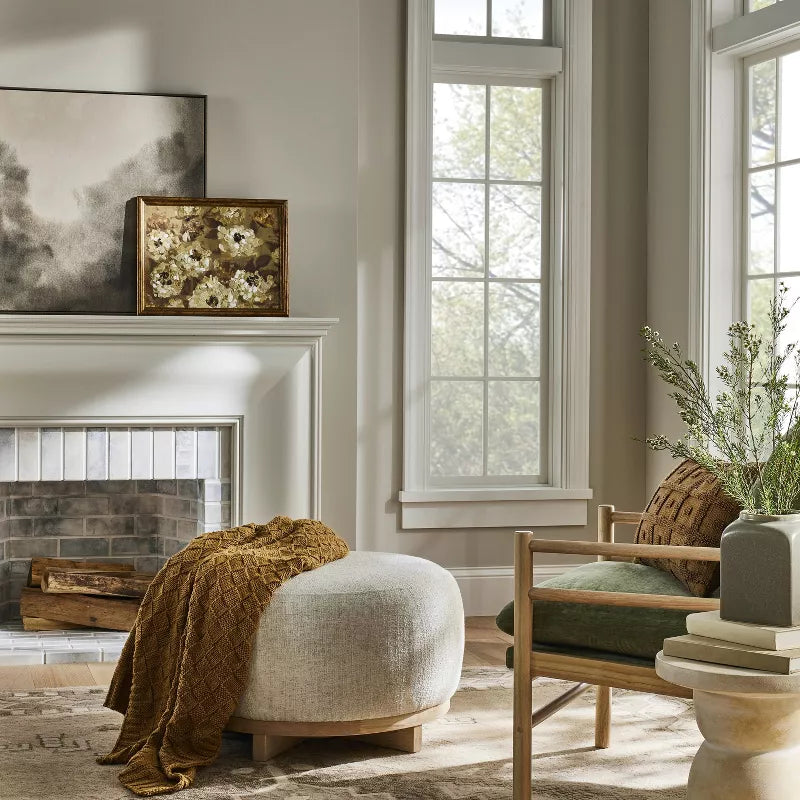 Cozy living room with a fireplace, armchair, ottoman, and decorative elements.
