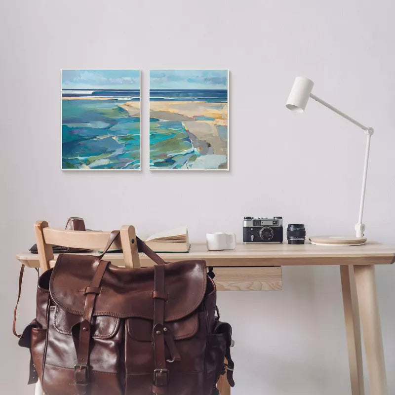 Desk with a leather backpack, camera, and lamp, featuring abstract art on the wall.