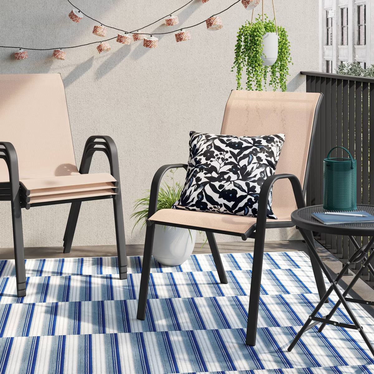 A chair with a beige colored fabric seat and backrest, featuring a black colored metal frame and armrests