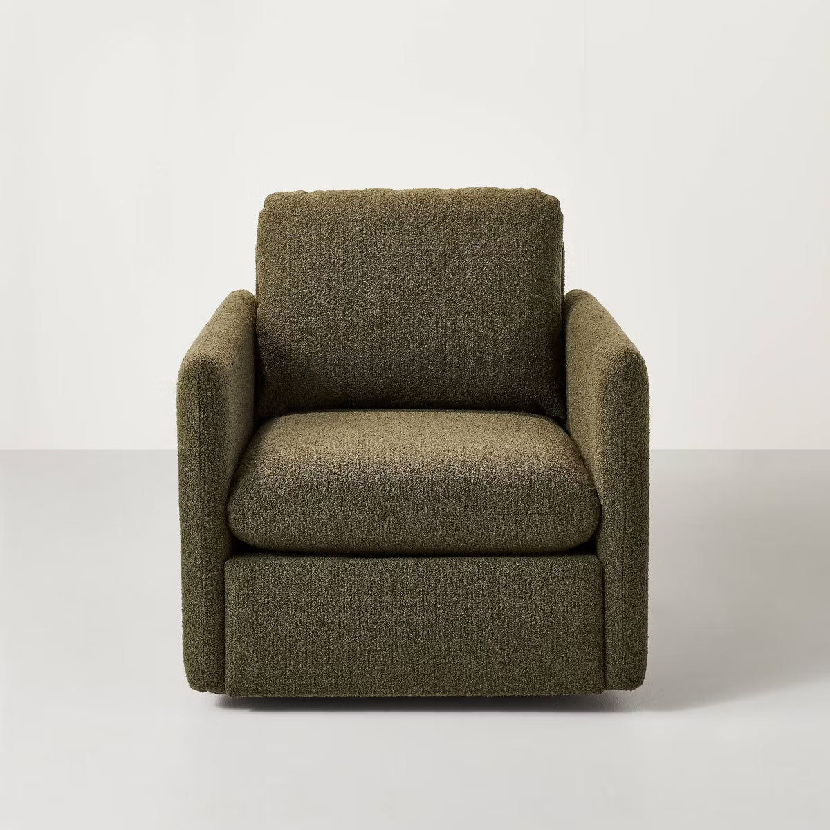 A greenish brown colored armchair with a textured fabric and square shape, placed on a light gray floor.