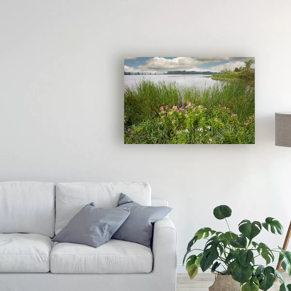 Landscape painting of a lake and grassy area in a living room setting.