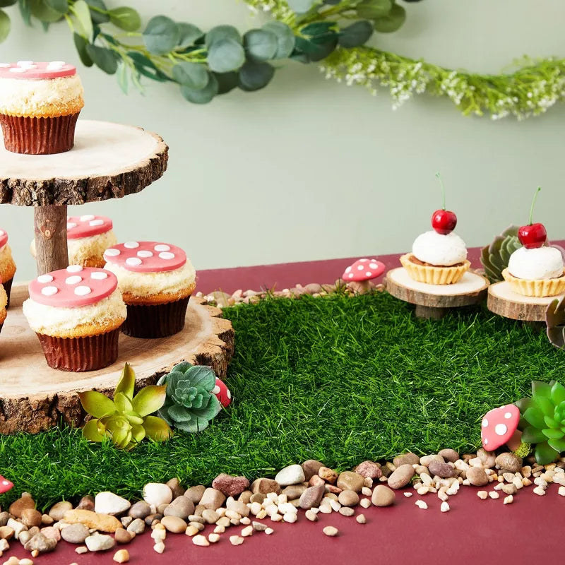 Decorative setup with cupcakes on a grassy patch and wooden stands.