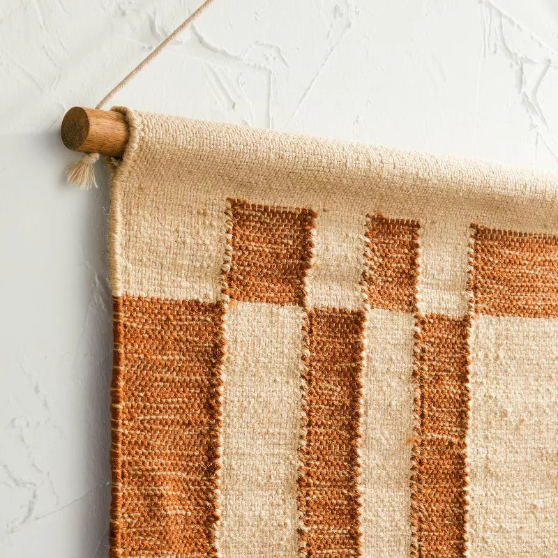 Decorative wall hanging with a checkered pattern above a wooden console table with decorative items.