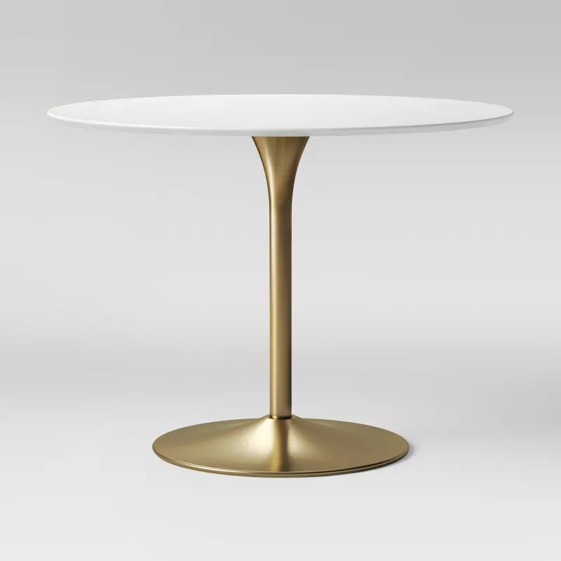 Round table with a white top and gold base on a light gray background