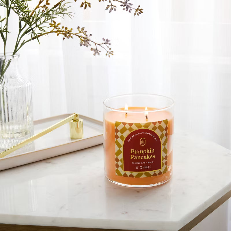 Candle labeled 'Pumpkin Pancakes' on a marble surface with a vase and tray in the background 15.1oz