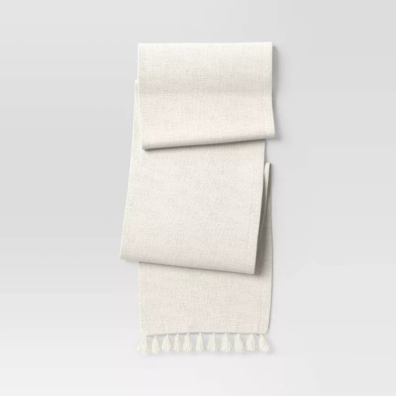 Folded white towel with tassels on a light gray background