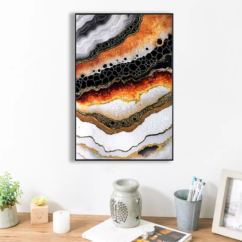 Abstract art print with orange, black, and white colors on a wall above a desk.