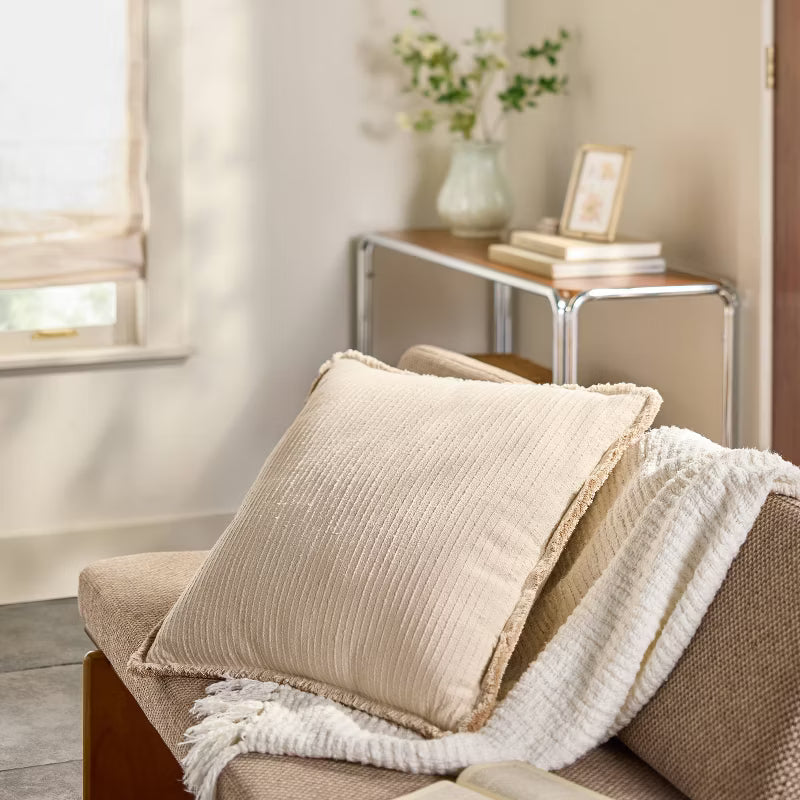 Beige textured pillow with a brand label on a green background Tan