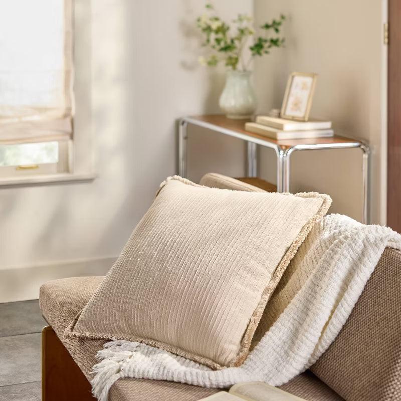 Beige textured pillow with a brand label on a green background Tan