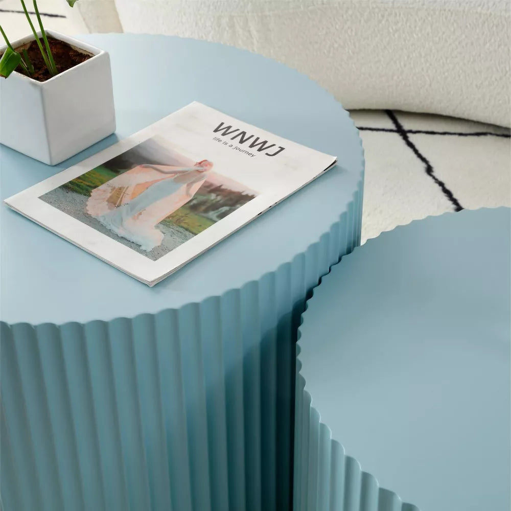 Blue ribbed side table with a magazine on top, featuring a plant and white vase.blue