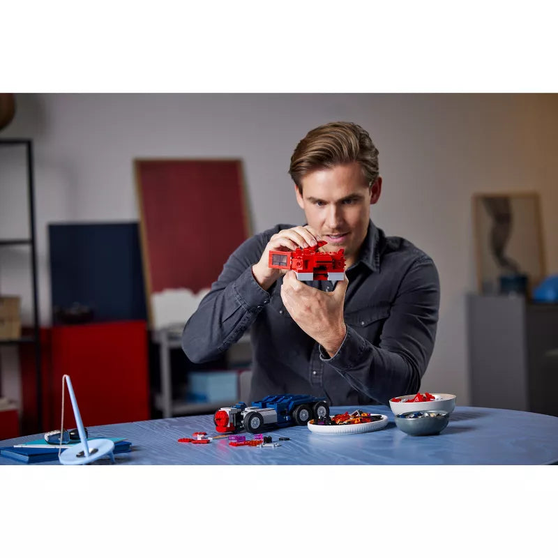 Man playing with toy cars and a remote control in a room.