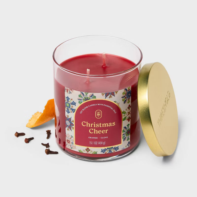 Candle labeled 'Christmas Cheer' on a table with a decorative background 15.1oz