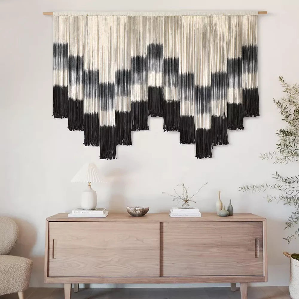 Black and white patterned wall art with fringe on a white background