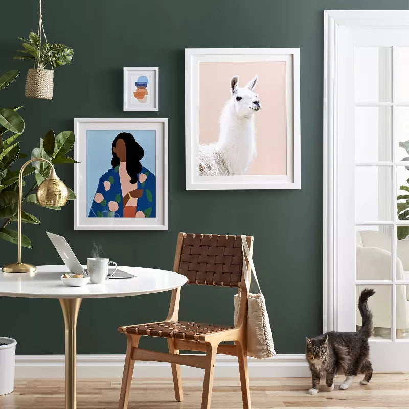 Modern living room with a green wall, framed artwork, and a cat on the floor.