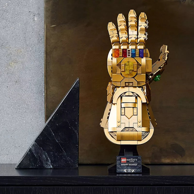 Gold LEGO Infinity Gauntlet on a dark surface with a marble wall background