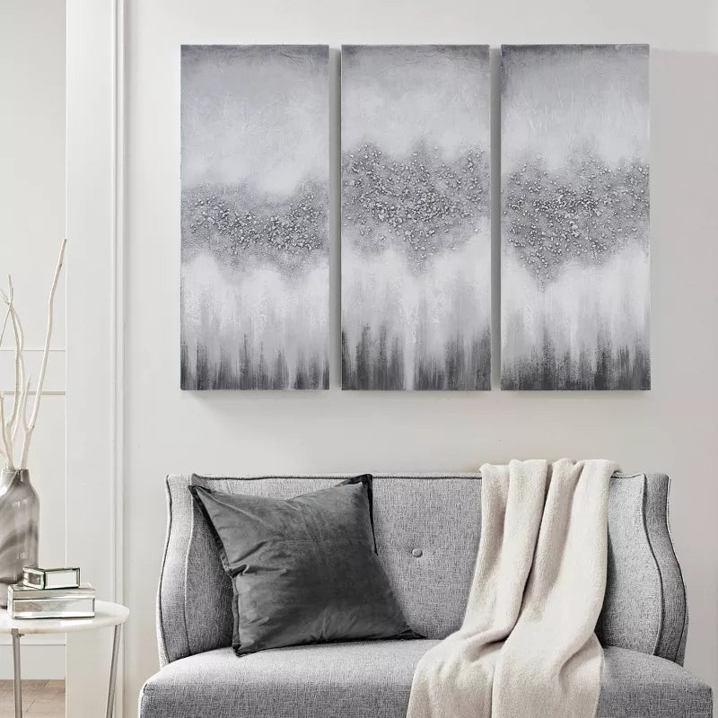Gray sofa with decorative pillows and a blanket, featuring abstract wall art in a modern living room.