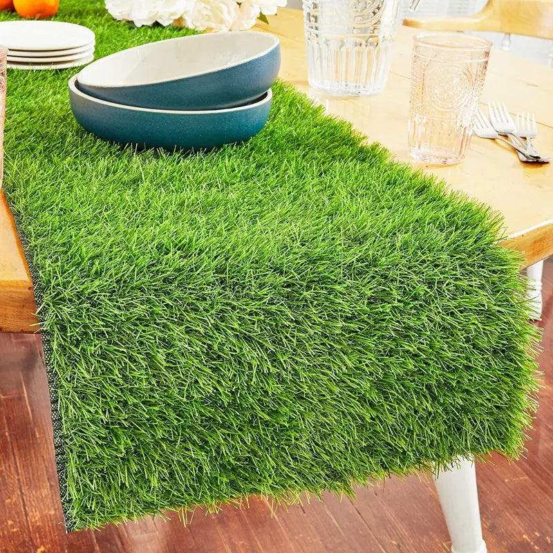 Green grass-like table runner on a wooden table with bowls and glasses.