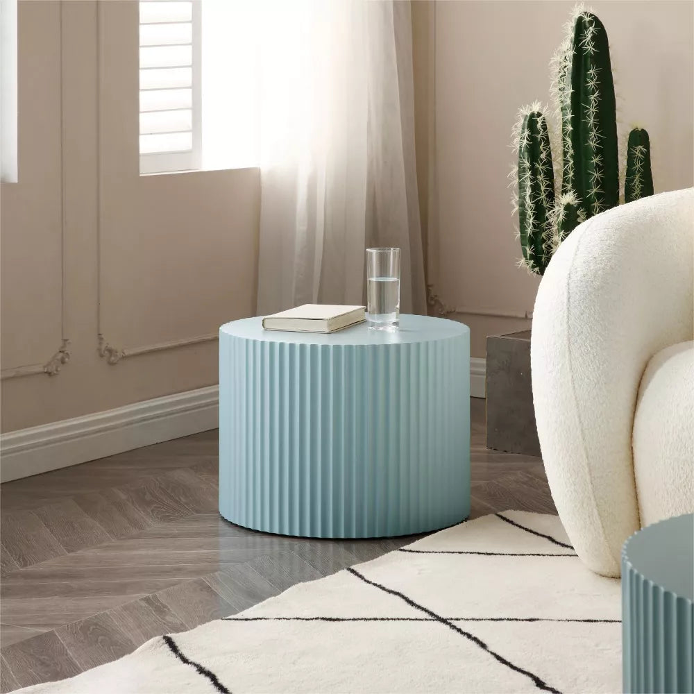 Blue ribbed side table with a magazine on top, featuring a plant and white vase.blue