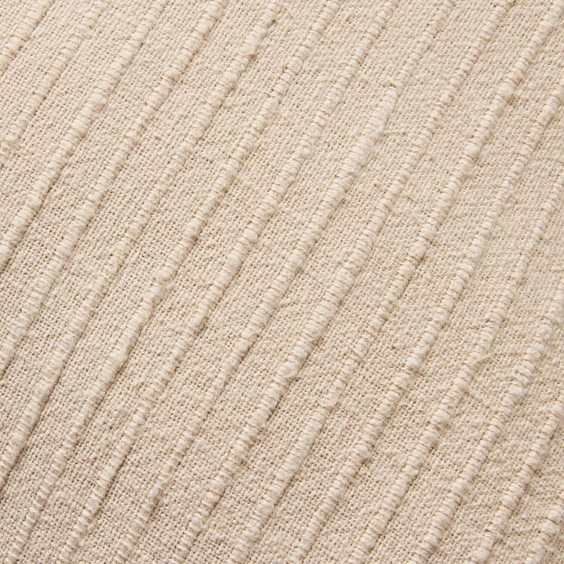 Beige textured pillow with a brand label on a green background Tan