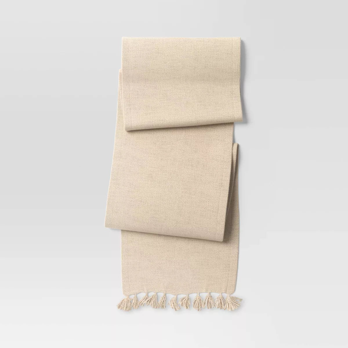 Beige towel with tassels on a light gray background