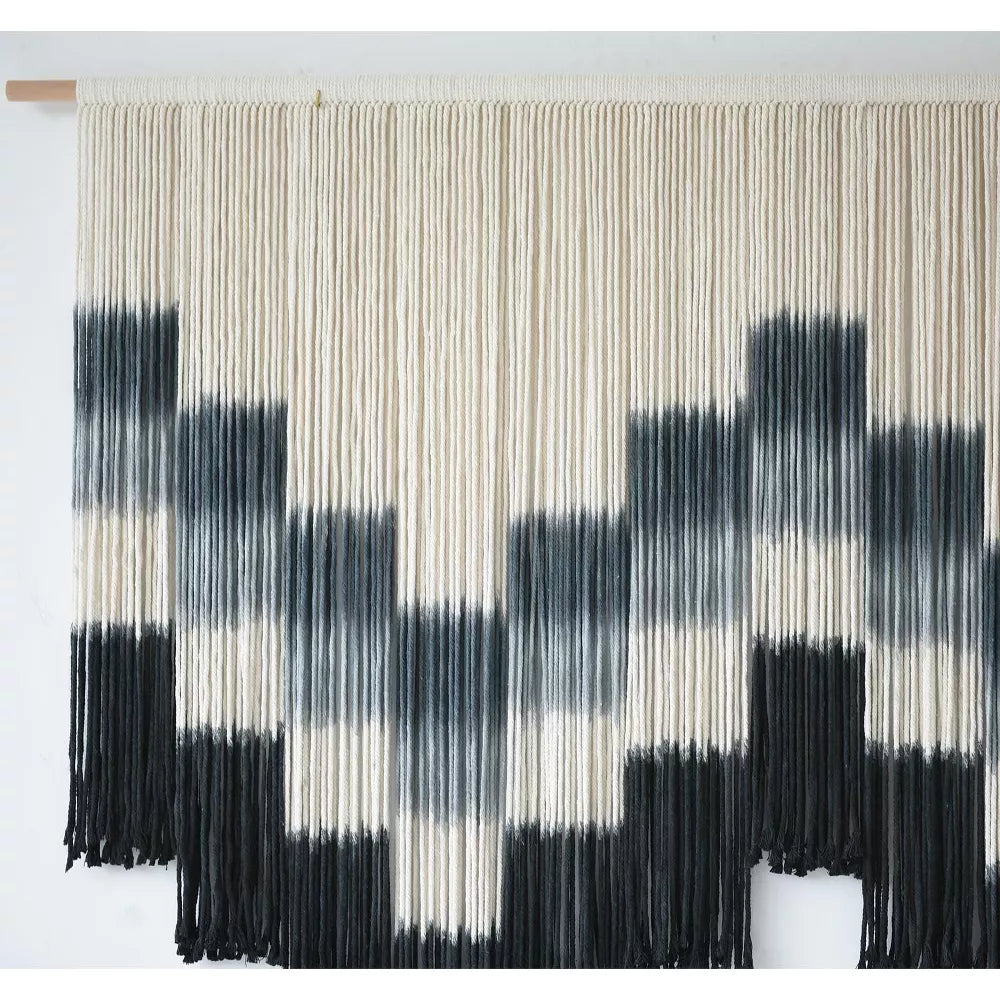 Black and white patterned wall art with fringe on a white background