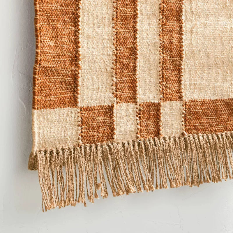 Decorative wall hanging with a checkered pattern above a wooden console table with decorative items.