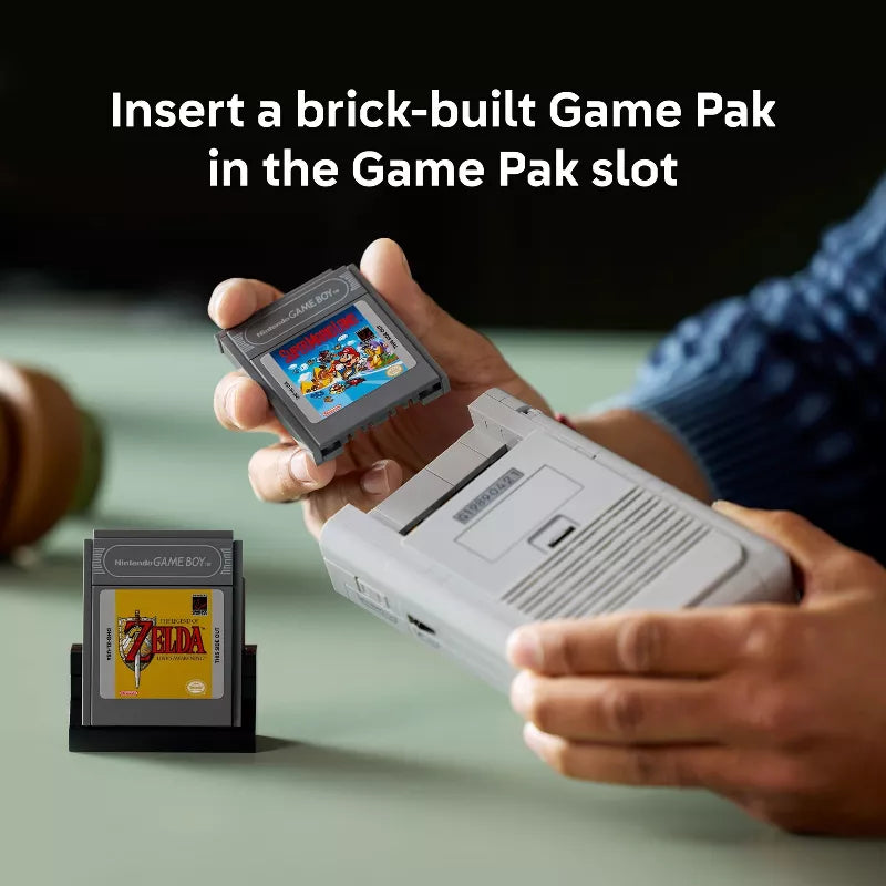 Hand holding a brick-built Game Pak with a Game Boy, showing 'The Legend of Zelda' cartridge.