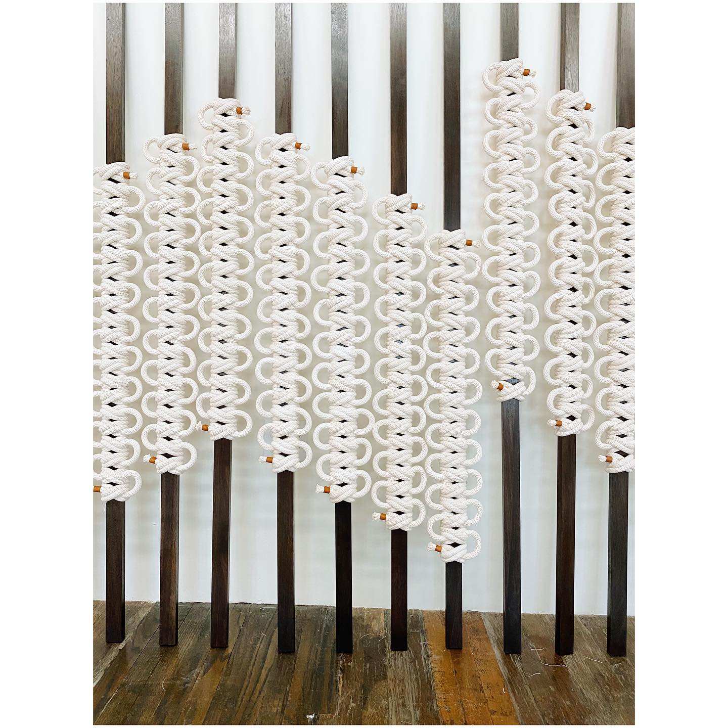 Decorative screen with wavy white design on a wooden floor and striped wall background