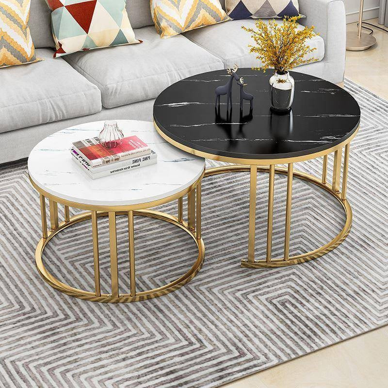Two round coffee tables with gold frames on a patterned rug, with a sofa and decorative pillows in the background black White