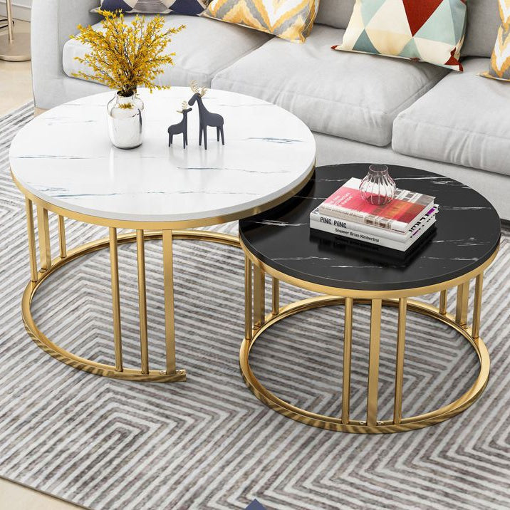 Two round coffee tables with gold frames on a patterned rug, with a sofa and decorative pillows in the background black White