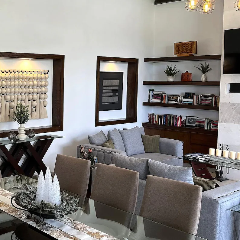 Living room with gray sectional sofa, glass dining table, and bookshelf.