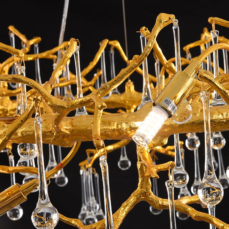 Gold branch-like chandelier with hanging clear glass droplets on a black background
