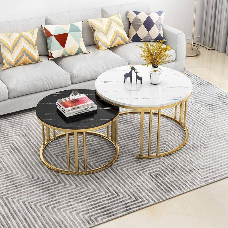 Two round coffee tables with gold frames on a patterned rug, with a sofa and decorative pillows in the background black White