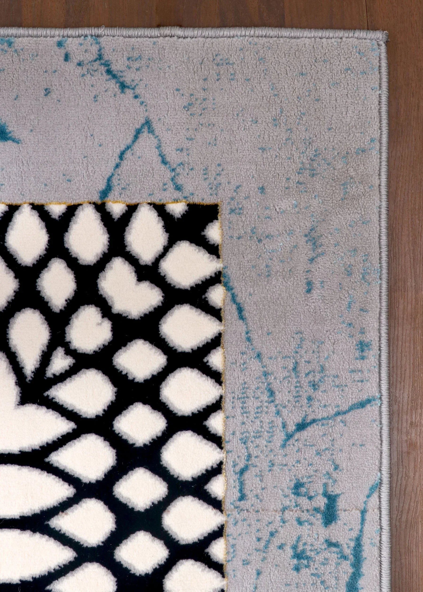 Close-up of a rug with geometric patterns on a wooden floor.