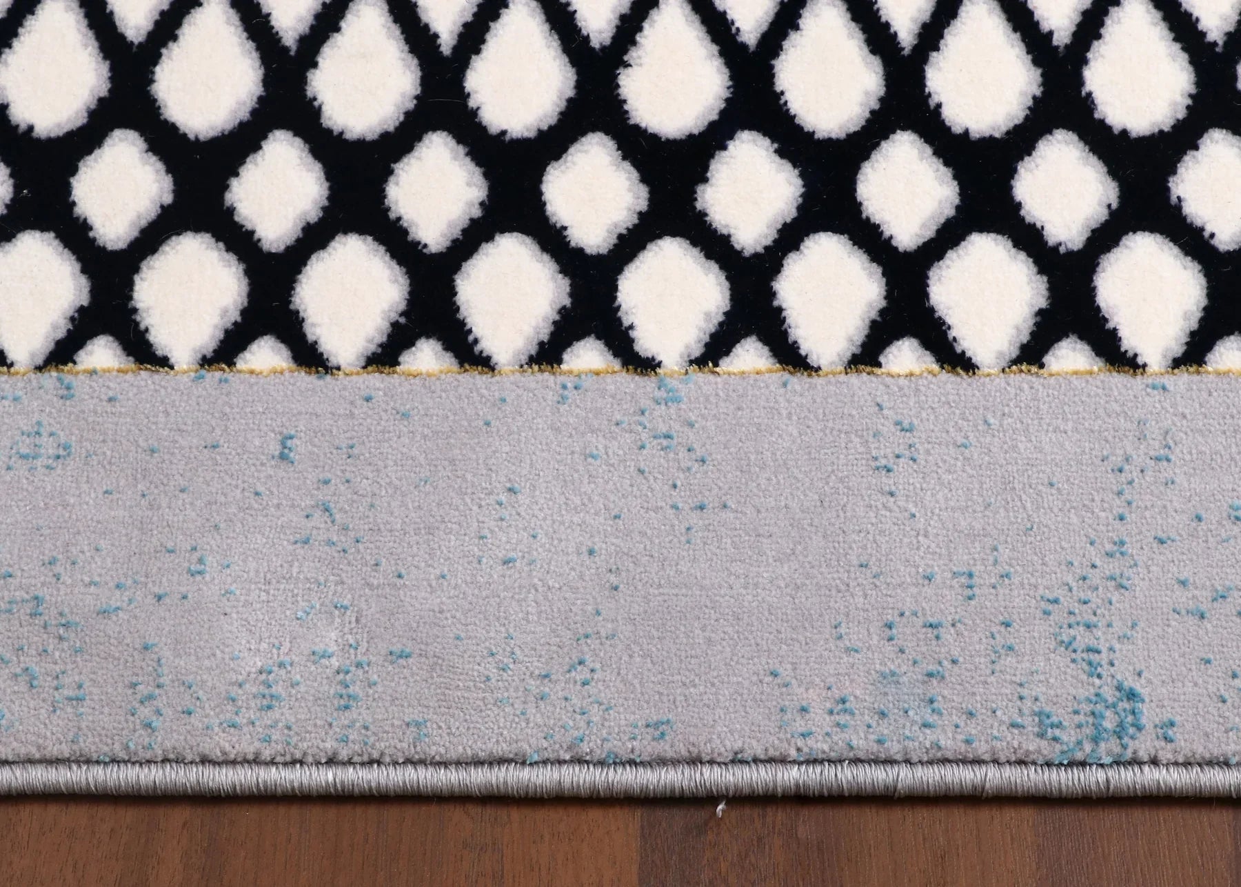 Close-up of a rug with geometric patterns on a wooden floor.