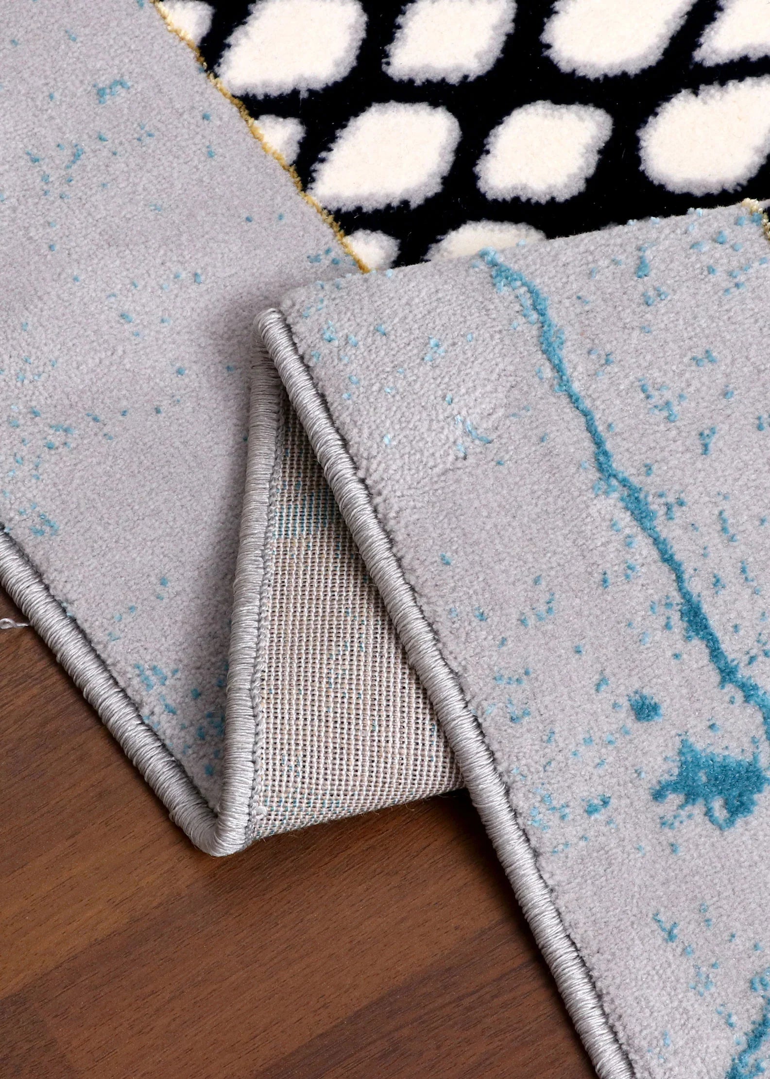 Close-up of a rug with geometric patterns on a wooden floor.
