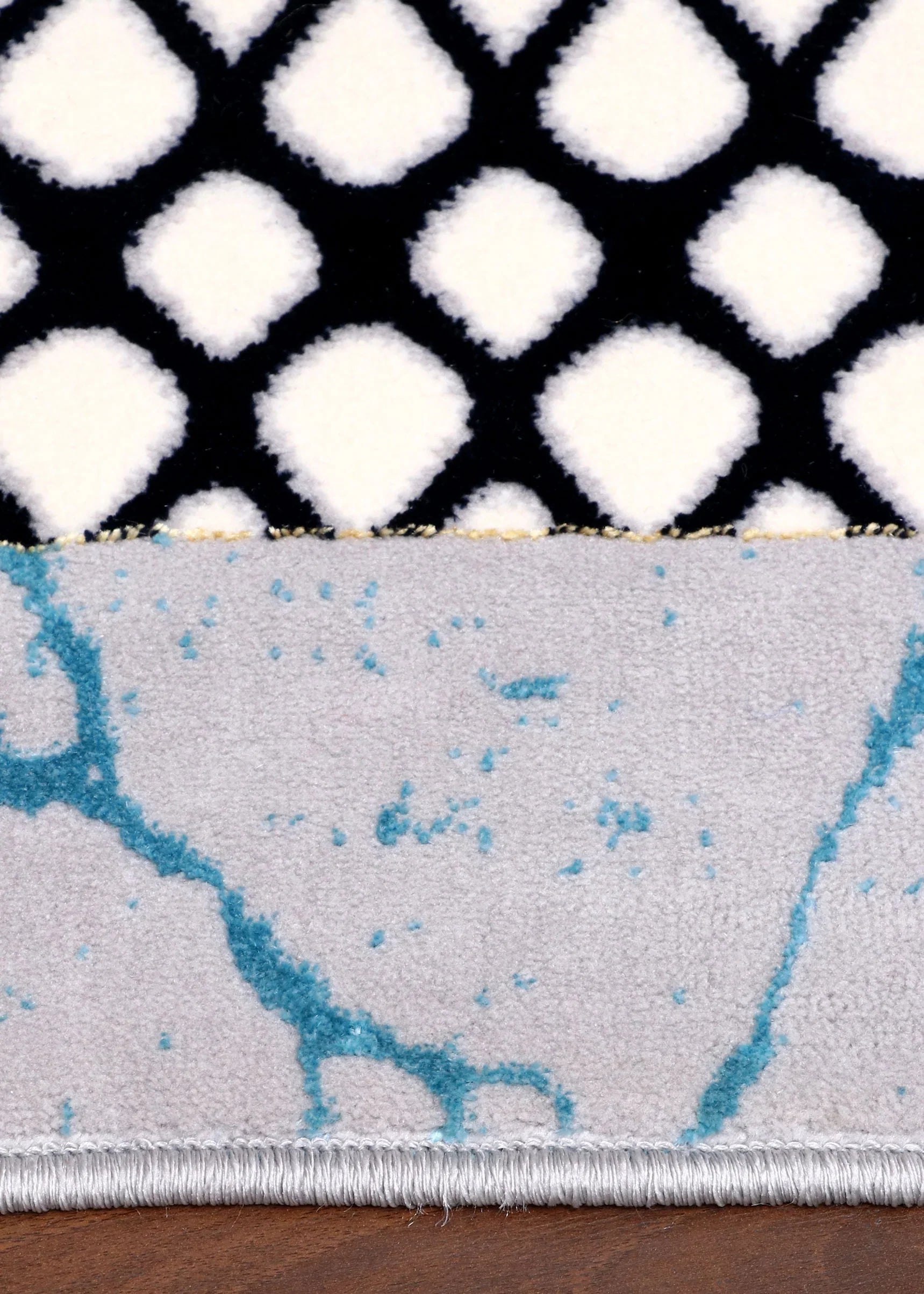 Close-up of a rug with geometric patterns on a wooden floor.