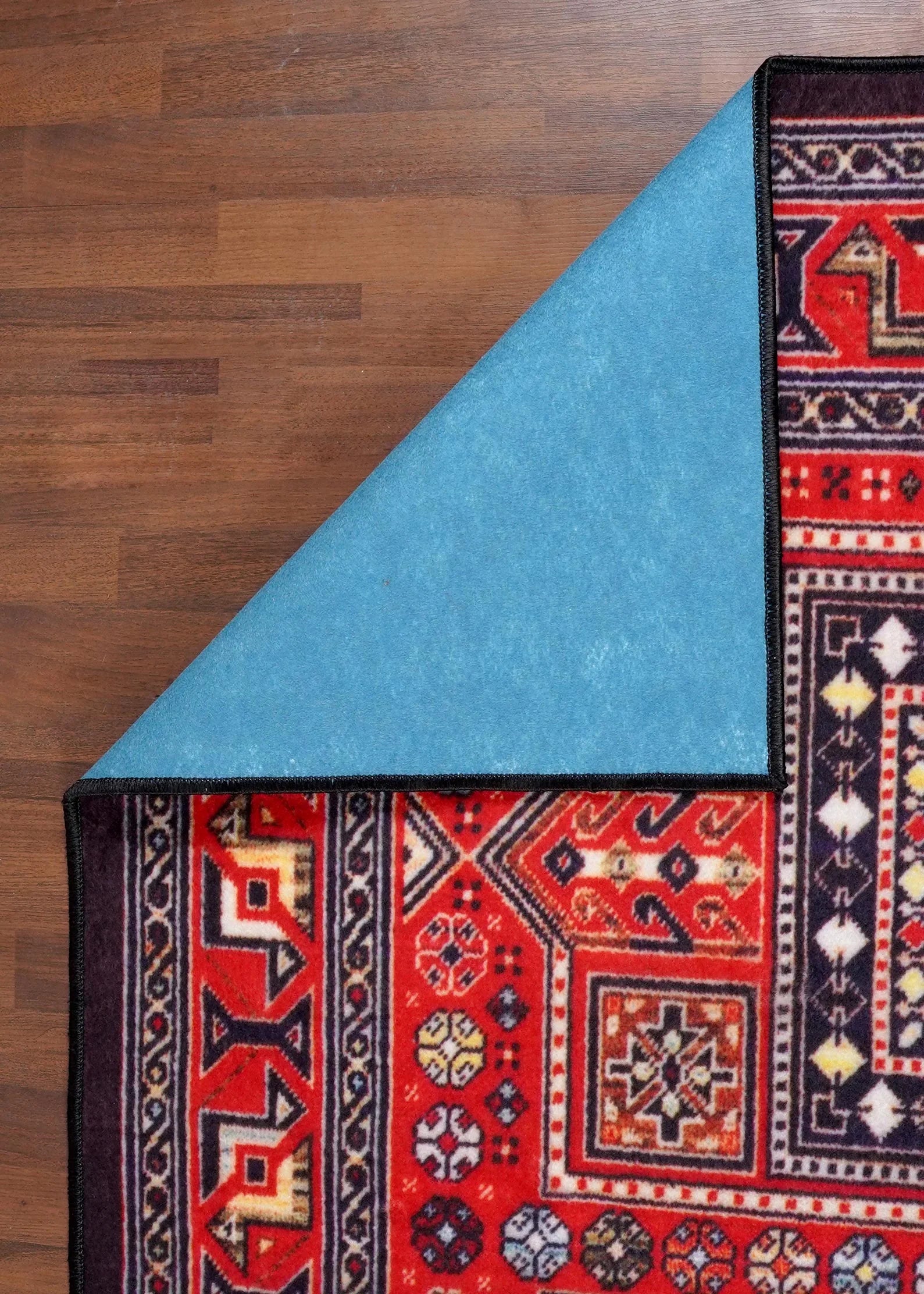 Close-up of a red and black patterned rug on a wooden floor.