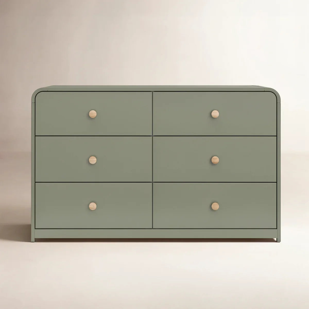 A modern six-drawer dresser in a muted sage green with small round light wood knobs, shown against a neutral beige background.