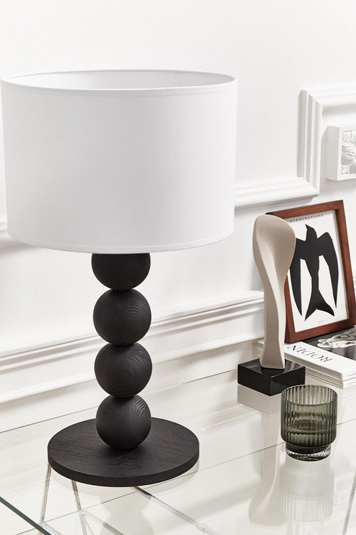 Table lamp with a white shade and black cylindrical base on a light gray background