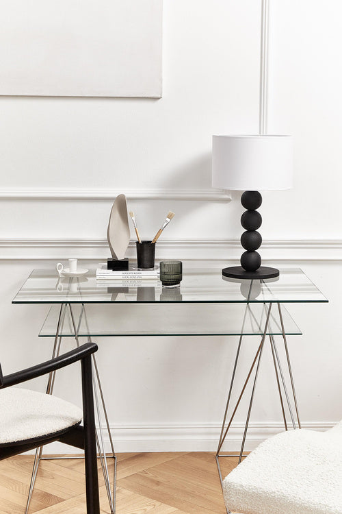 Table lamp with a white shade and black cylindrical base on a light gray background