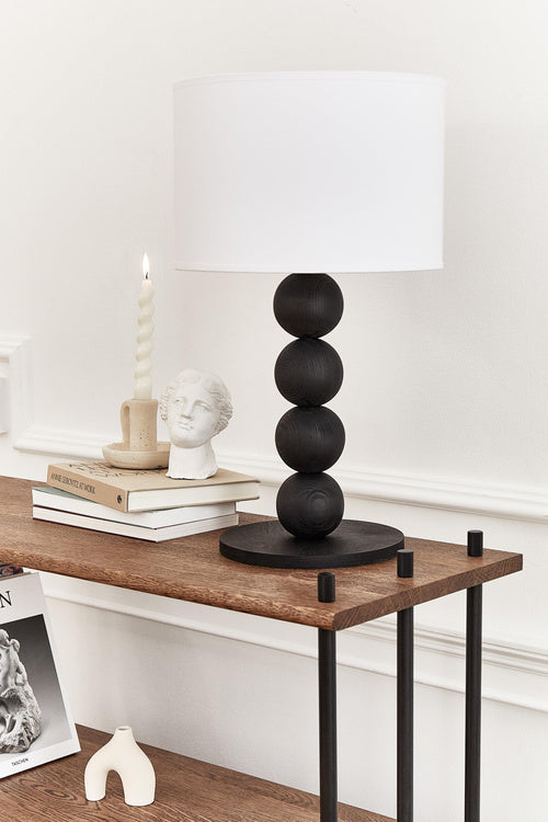 Table lamp with a white shade and black cylindrical base on a light gray background