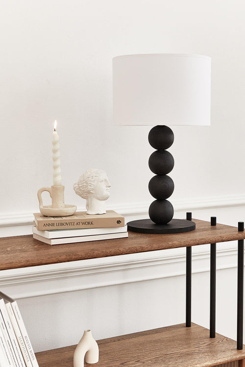 Table lamp with a white shade and black cylindrical base on a light gray background